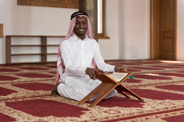 Hombre musulmán africano negro haciendo oración tradicional a Dios mientras usa una gorra tradicional Dishdasha