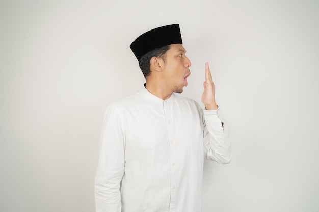 Hombre musulmán asiático cubriendo su boca con la mano o mal aliento usando traje árabe en aislado
