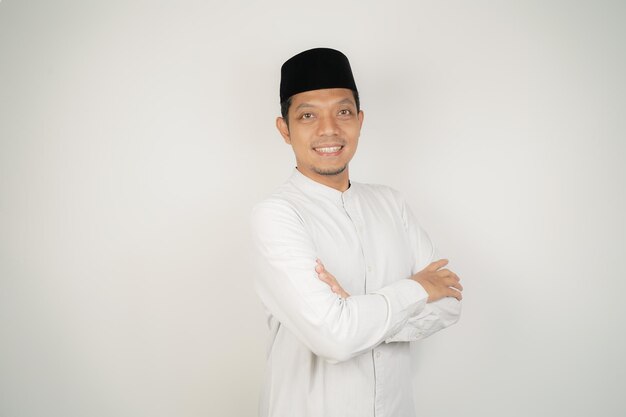 Hombre musulmán asiático feliz y confiado de pie con los brazos cruzados sobre un fondo blanco