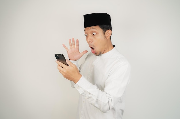 Hombre musulmán asiático feliz y sonriente de pie con el gesto de saludo de Eid Mubarak y la bienvenida al Ramadán