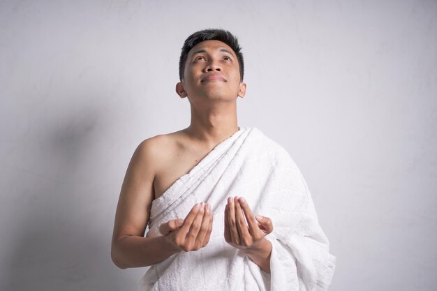 Foto hombre musulmán asiático con ropa blanca de ihram muestra rezando
