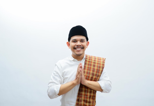 Hombre musulmán asiático con ropa blanca y sarung sonriendo da un saludo durante el Ramadán Eid Al Fitr