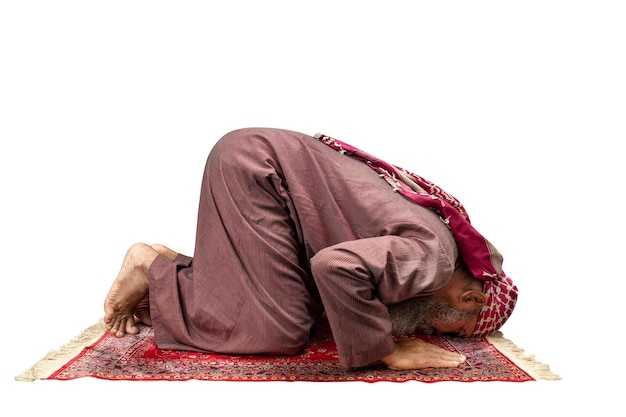 Hombre musulmán con barba usando keffiyeh con agal en posición de oración salat en la alfombra de oración
