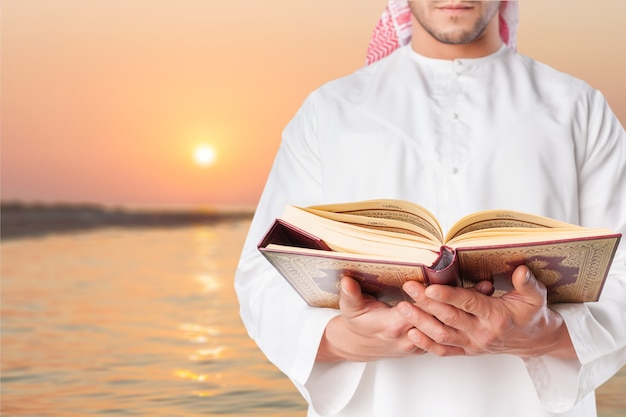 Hombre musulmán leyendo el Corán en el fondo del mar al atardecer