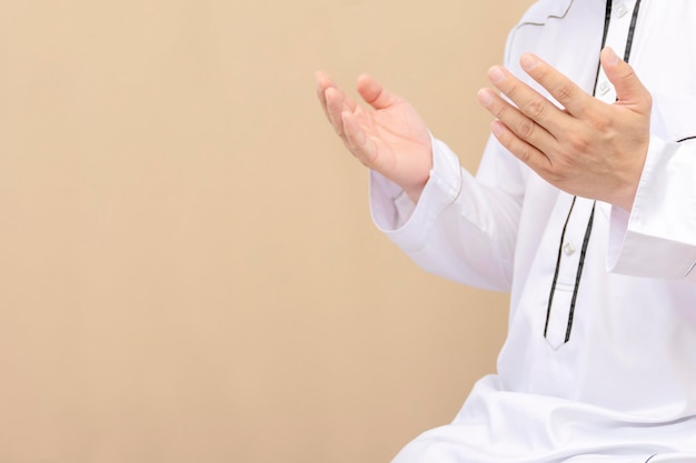 Hombre musulmán religioso rezando dentro de la mezquita. Los hombres están rezando por su Dios del Islam. Ponga el vestido blanco puro en los dos lados de la boca. La fe islámica.