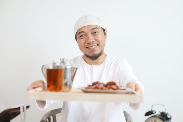 Hombre musulmán sonriente dando comida y bebidas Iftar para el desayuno en el mes de Ramadán