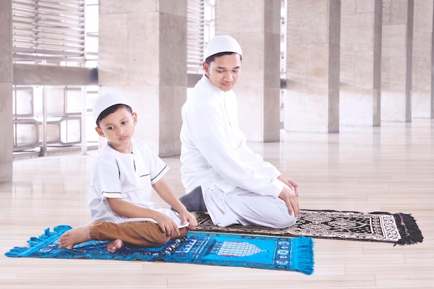 Hombre musulmán con su hijo orando en la mezquita