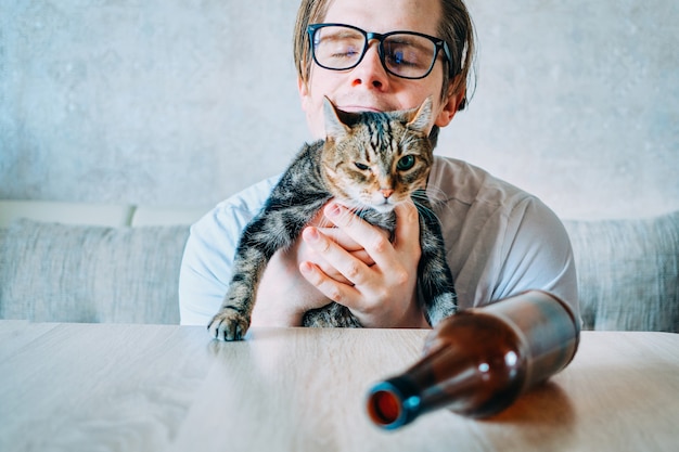 Foto un hombre muy borracho abraza a un gato.