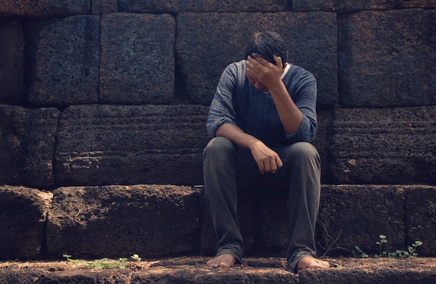 un hombre muy triste y deprimido sentado cerca de una pared