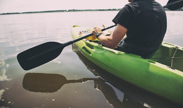 El hombre nada en un kayak en el lago