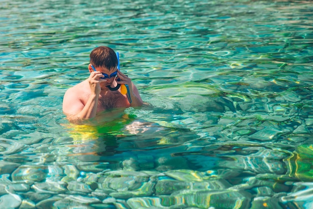 Hombre nadando bajo el agua con máscara y cámara de acción