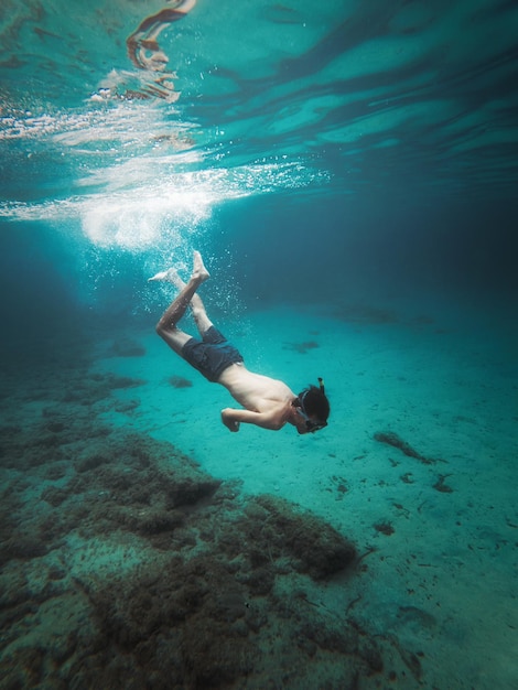 Un hombre nadando bajo el agua con la palabra océano en el fondo.