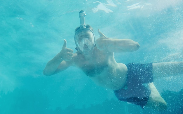 Hombre nadando bajo el agua en la piscina durante el día divirtiéndose