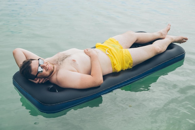hombre nadando en un colchón en el mar concepto de horario de verano