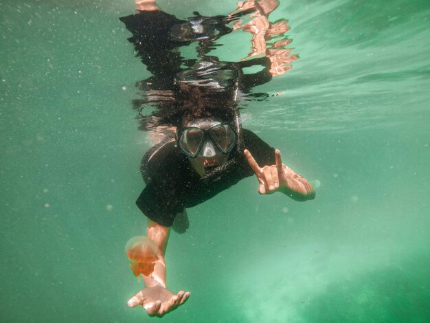 Foto hombre nadando en el mar con medusas