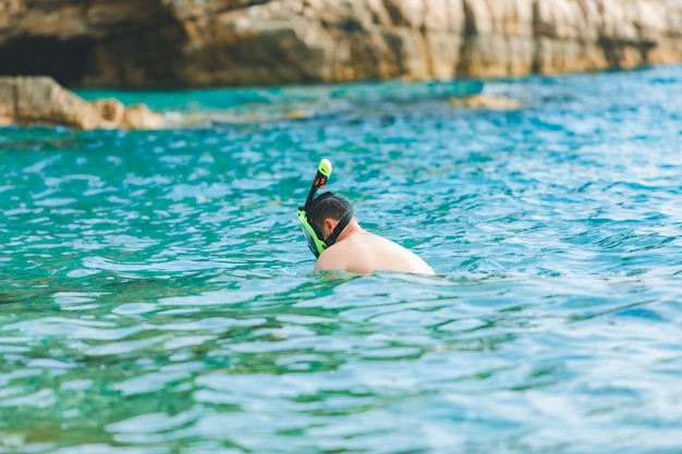 Hombre nadando con máscara de snorkel en el espacio de copia de agua de mar azul celeste