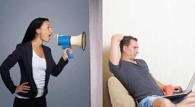 Hombre navegando por internet mientras una mujer enojada lo llama a través de un megáfono
