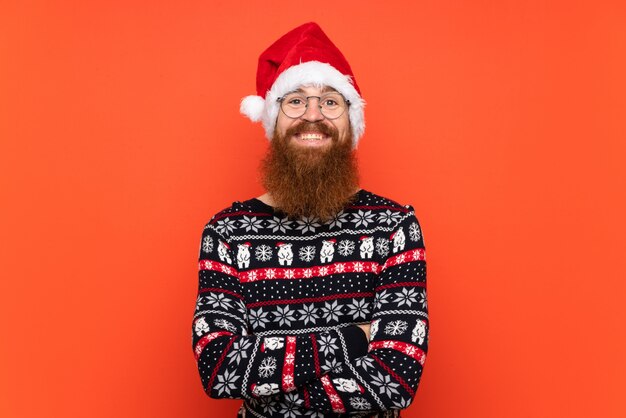 Hombre de Navidad con barba larga sobre pared roja aislada sonriendo mucho