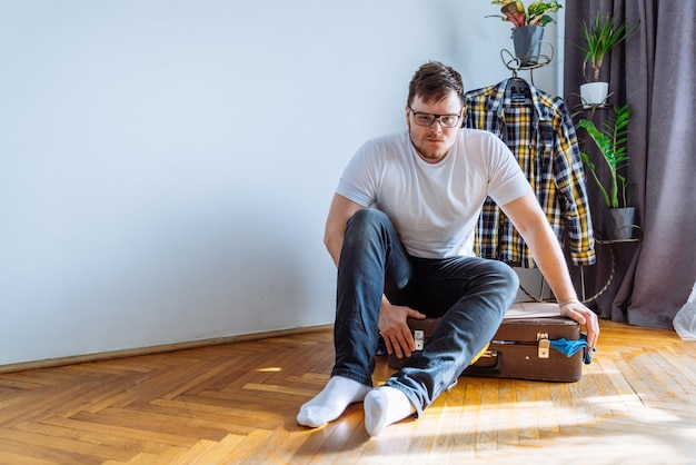 Foto hombre necesita ayuda para cerrar la maleta sobrecargada bolsa con ropa concepto de viaje