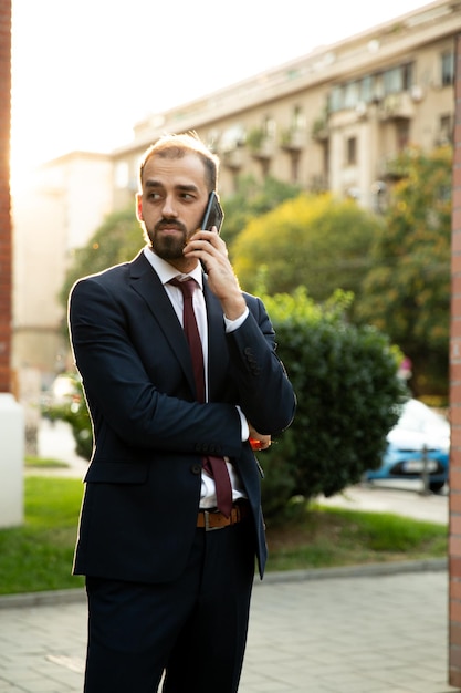 Hombre de negocios acertado hablando por teléfono al atardecer. Estilo de negocios y calle