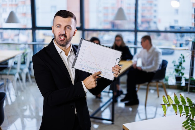Foto un hombre de negocios adulto con una carpeta en las manos se encuentra en la oficina en el contexto de sus empleados