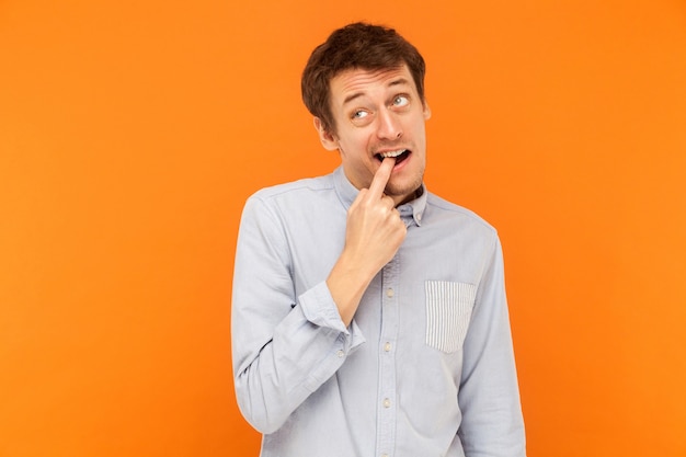 Foto hombre de negocios adulto joven divertido tocar los dientes del dedo y mirando hacia arriba