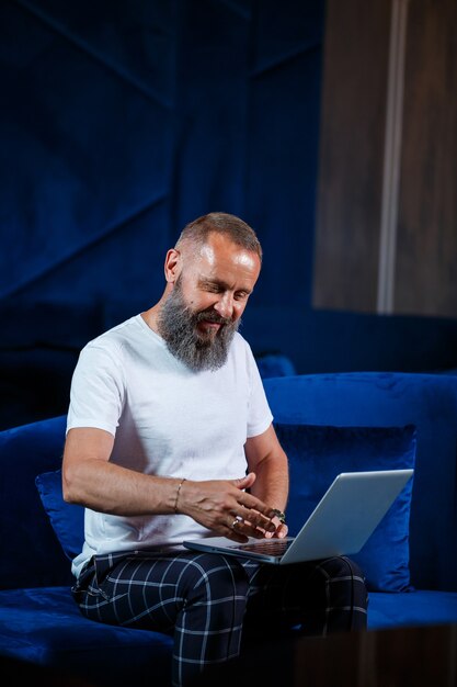 Foto hombre de negocios adulto, profesor, mentor trabajando en un nuevo proyecto. se sienta junto a una gran ventana sobre la mesa. mira la pantalla del portátil.