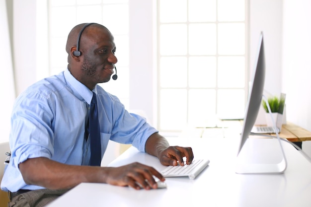 Hombre de negocios afroamericano con auriculares trabajando en su computadora portátil