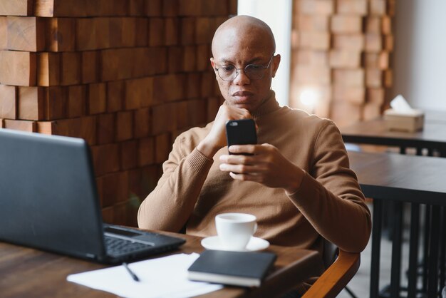 Hombre de negocios afroamericano con laptop en un café