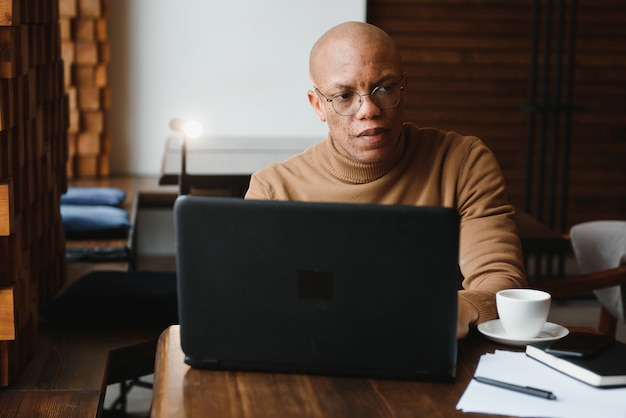 Hombre de negocios afroamericano con laptop en un café