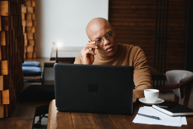 Hombre de negocios afroamericano con laptop en un café