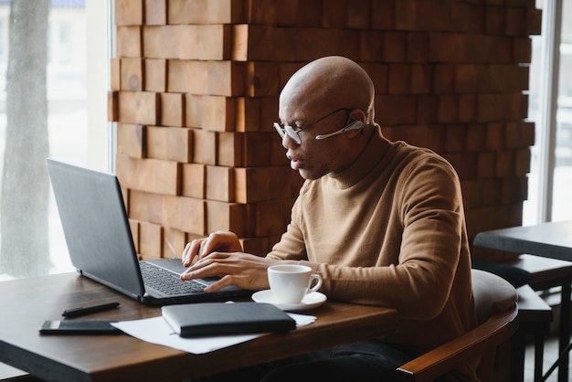 Hombre de negocios afroamericano con laptop en un café