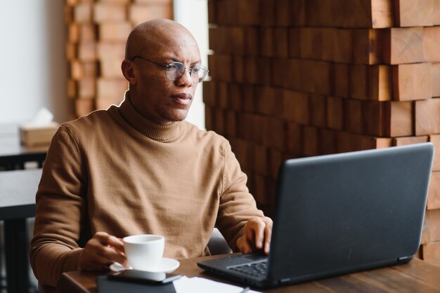 Hombre de negocios afroamericano con laptop en un café