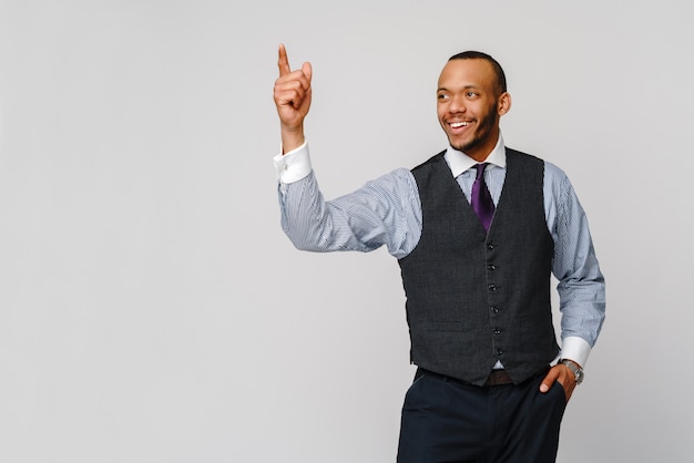 Hombre de negocios afroamericano que aparece con el dedo sobre la pared gris