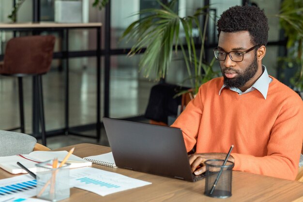 hombre de negocios afroamericano sentado en la computadora portátil en la oficina