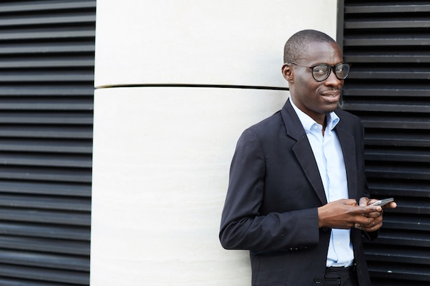 Hombre de negocios afroamericano con smartphone al aire libre