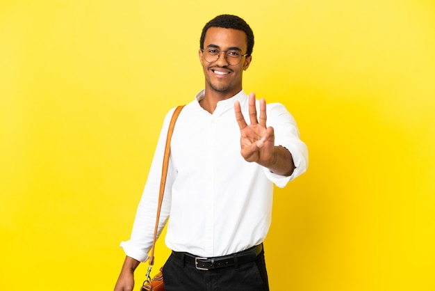 Hombre de negocios afroamericano sobre fondo amarillo aislado feliz y contando tres con los dedos