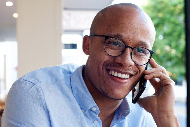 Hombre de negocios afroamericano sonriendo y hablando por teléfono móvil