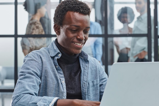 hombre de negocios afroamericano sonriente con ejecutivos trabajando en el fondo