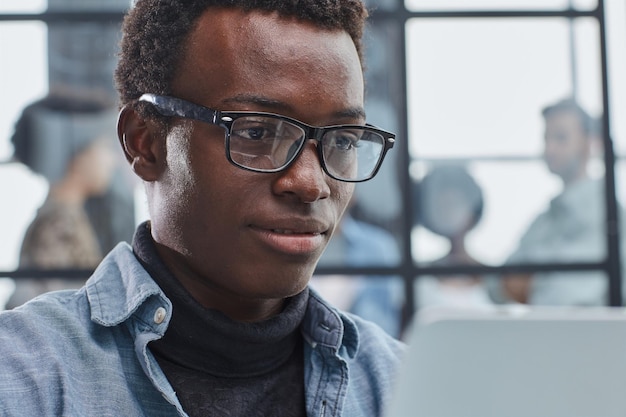 hombre de negocios afroamericano sonriente con ejecutivos trabajando en el fondo