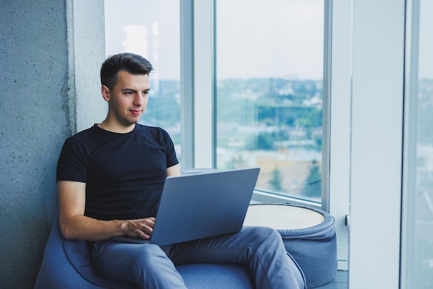 Un hombre de negocios alegre está sentado trabajando con una computadora portátil en la oficina Un hombre de negocios está sentado y trabajando en una computadora portátil Comenzando el día en la oficina