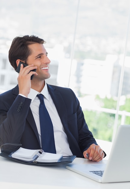 Hombre de negocios alegre que tiene una llamada telefónica