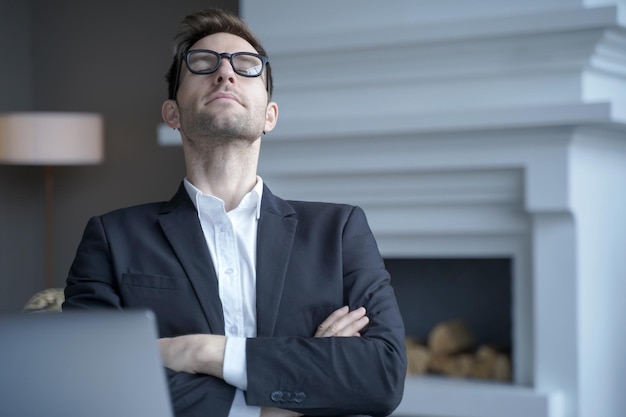 Un hombre de negocios alemán mediador se sienta en el escritorio con los ojos cerrados descansando del trabajo de la computadora