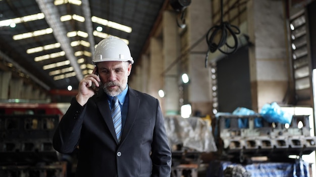 El hombre de negocios en el almacén de la fábrica está hablando por teléfono móvil