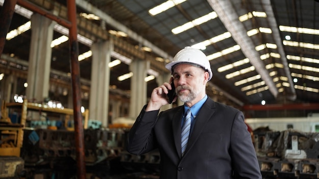 El hombre de negocios en el almacén de la fábrica está hablando por teléfono móvil