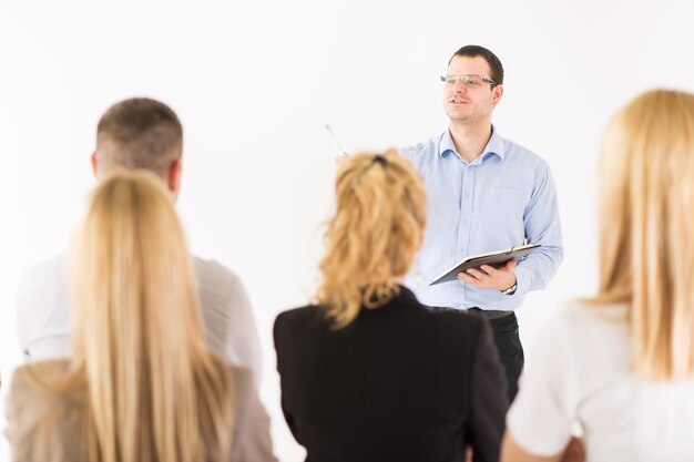 Un hombre de negocios amable explicando el plan de trabajo frente a sus compañeros de trabajo. El equipo está escuchando.