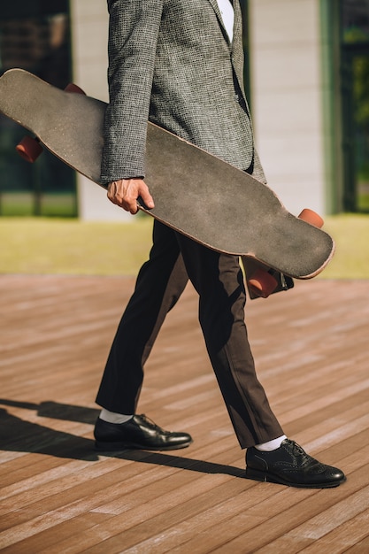 Un, hombre de negocios, ambulante, con, un, patineta, en, manos