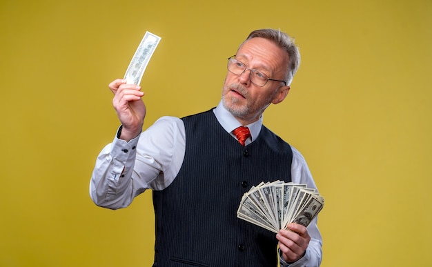 Hombre de negocios anciano feliz con ventilador de billetes de un dólar