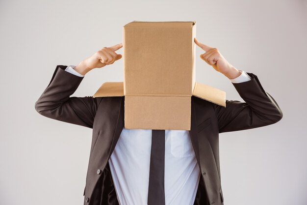 Hombre de negocios anónimo apuntando a la caja sobre fondo gris