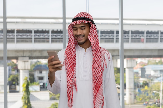 Hombre de negocios árabe árabe feliz mirando en el teléfono móvil